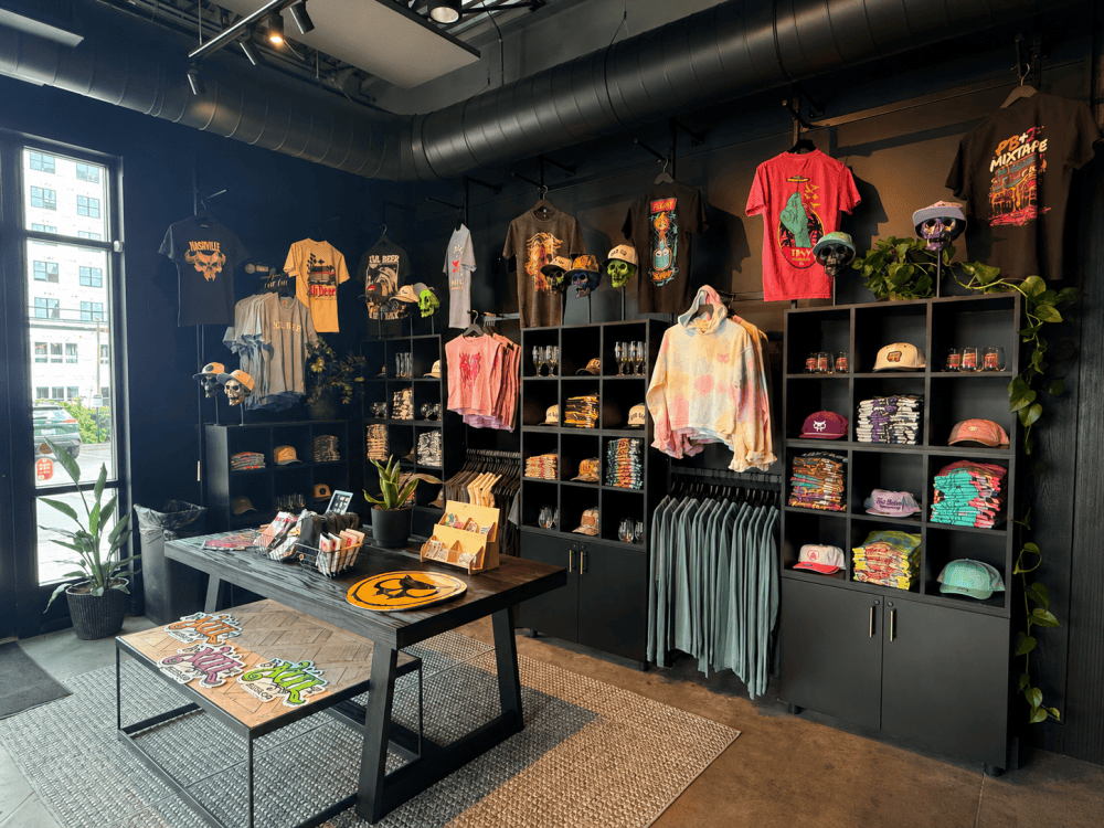 Xul Beer merchandise wall featuring shirts, hats, glassware, and accessories inside the West Nashville taproom in The Nations.
