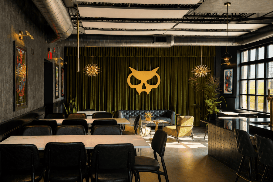Interior of Xul Beer Company’s renovated West Nashville taproom in The Nations, featuring olive green velvet, brass lighting, lounge seating, and the Xul skull.